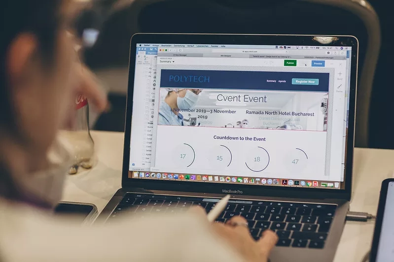 A person working on a laptop with an event website on the screen with a countdown timer.