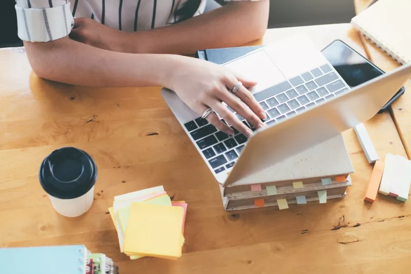 A woman is using a laptop on top of a stack of books.