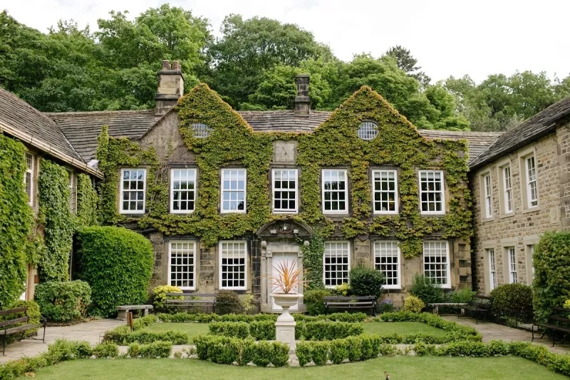 Stone building with ivy-covered walls and a circular garden with benches, showcasing green venues.