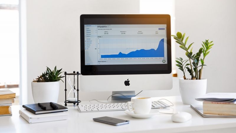 Apple computer sitting on desk with graph on screen