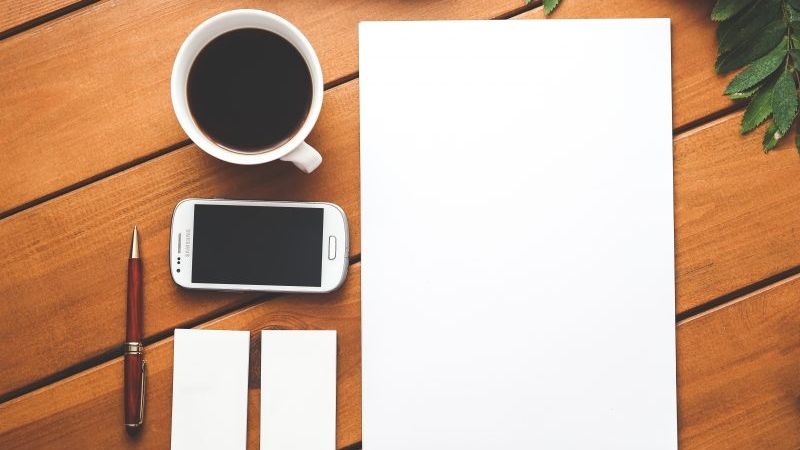 Blank paper, pen, coffee, mobile on table