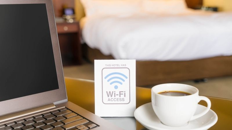 Laptop on hotel room table with wifi sign and coffee cup