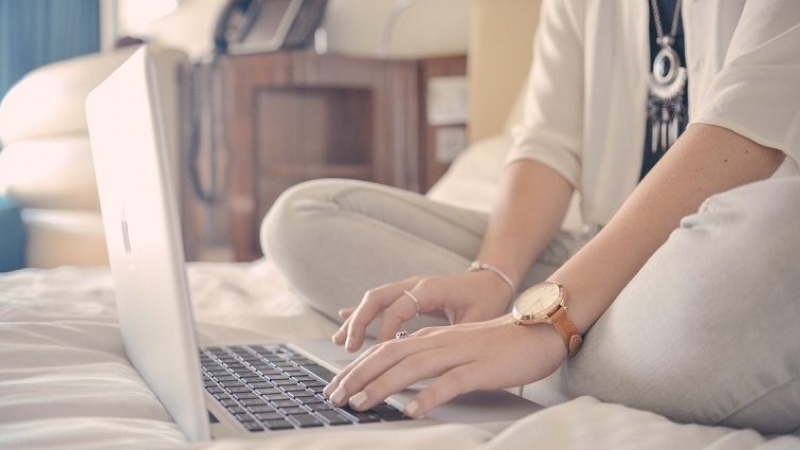 woman sat on bed using laptop