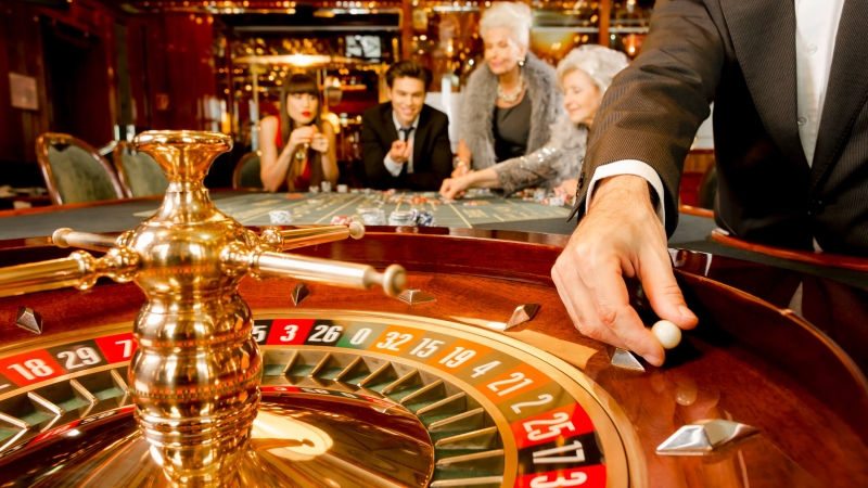 casino table with roulette wheel and players