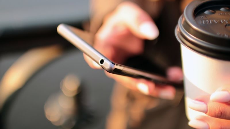 Person holding coffee and cell phone