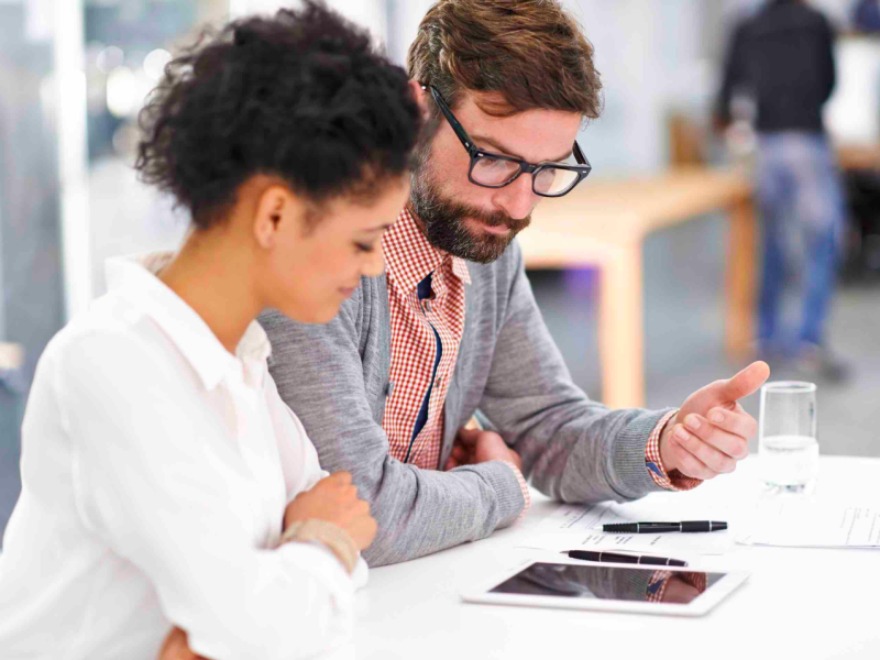 Man deliberating something with a woman sitting in an office